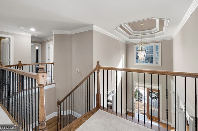 hallway featuring an inviting chandelier, hardwood / wood-style floors, ornamental molding, and a raised ceiling