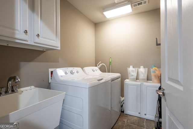 laundry area with cabinets, washer and dryer, sink, and dark tile patterned flooring