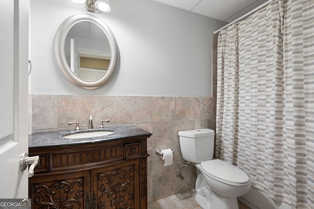 bathroom featuring toilet, a shower with curtain, tile walls, vanity, and a drop ceiling