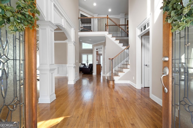 foyer entrance featuring hardwood / wood-style floors, ornamental molding, and decorative columns