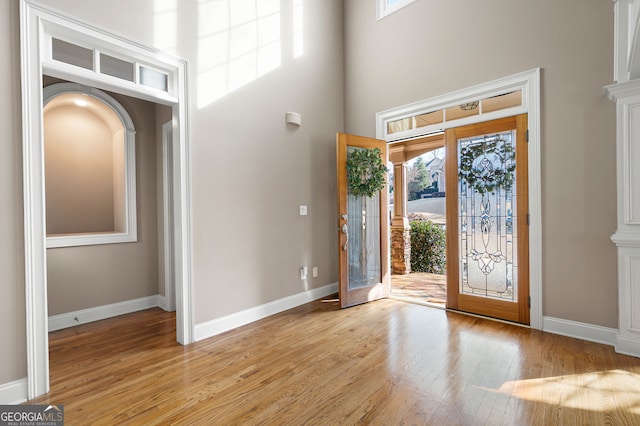 entryway with a high ceiling, light wood-type flooring, and french doors