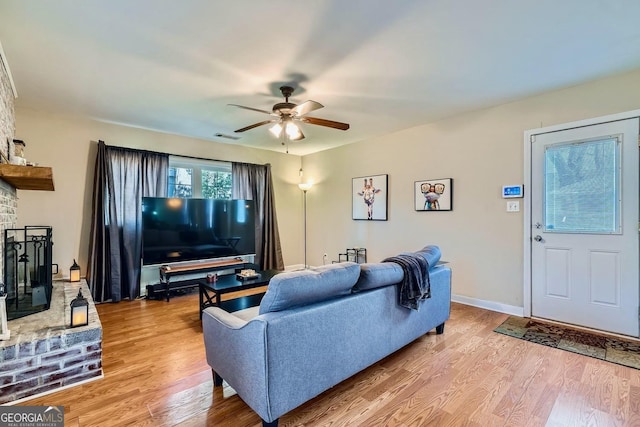 living room featuring a brick fireplace, hardwood / wood-style flooring, and ceiling fan