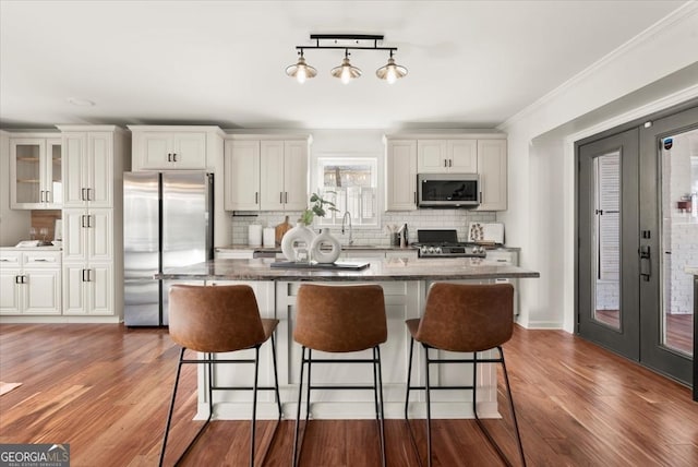 kitchen featuring white cabinets, appliances with stainless steel finishes, dark stone countertops, decorative backsplash, and sink