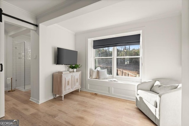 living area with light hardwood / wood-style flooring, crown molding, and a barn door