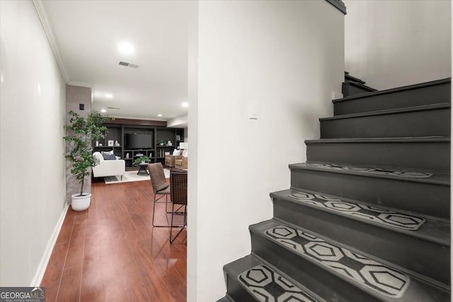 stairs featuring crown molding and hardwood / wood-style flooring