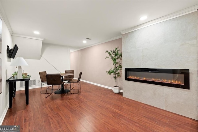 dining room featuring ornamental molding, hardwood / wood-style flooring, and a tile fireplace