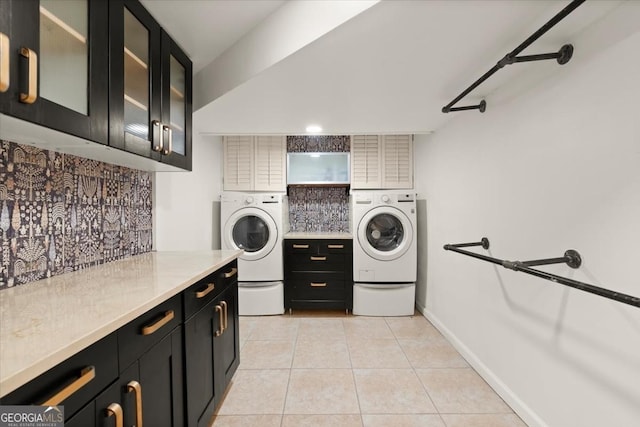 washroom with light tile patterned flooring, cabinets, and washer and dryer