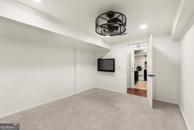 interior space featuring light carpet, ornamental molding, and washer / clothes dryer