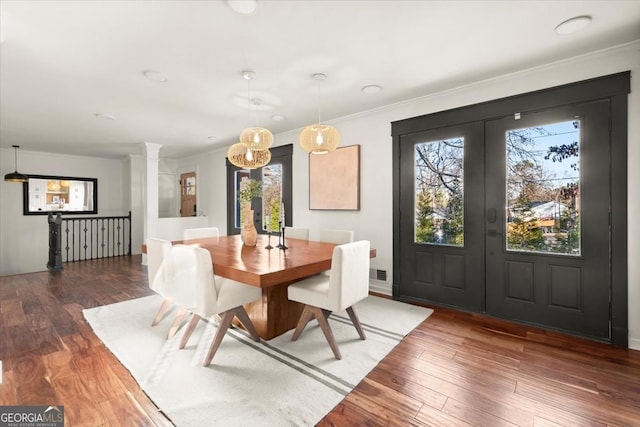 dining space featuring french doors, dark hardwood / wood-style floors, crown molding, and decorative columns