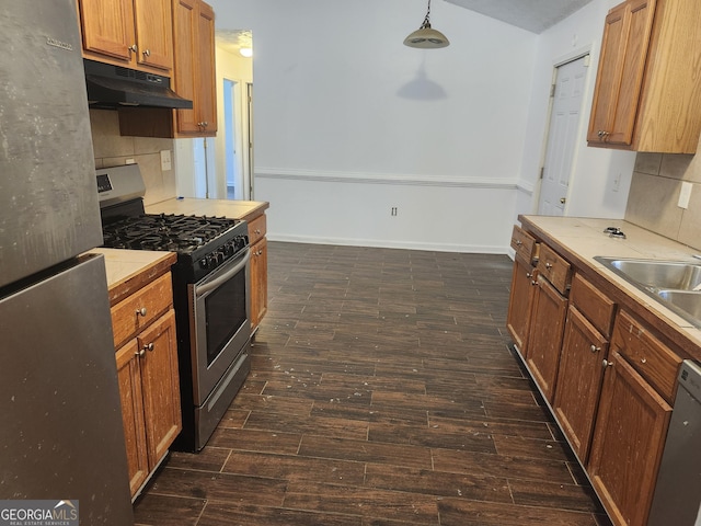 kitchen with appliances with stainless steel finishes, backsplash, dark hardwood / wood-style floors, pendant lighting, and sink