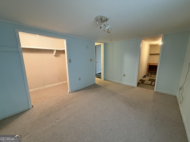 unfurnished bedroom with a walk in closet, a closet, light colored carpet, and baseboards