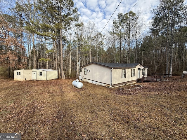 view of side of property featuring an outbuilding, a wooden deck, and a view of trees