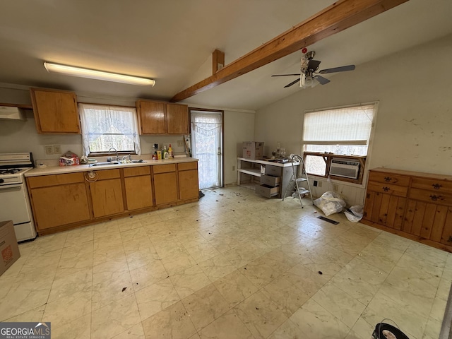 kitchen featuring lofted ceiling with beams, gas range gas stove, light countertops, light floors, and a sink