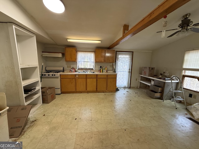 kitchen with white range with gas stovetop, brown cabinets, light countertops, light floors, and a sink