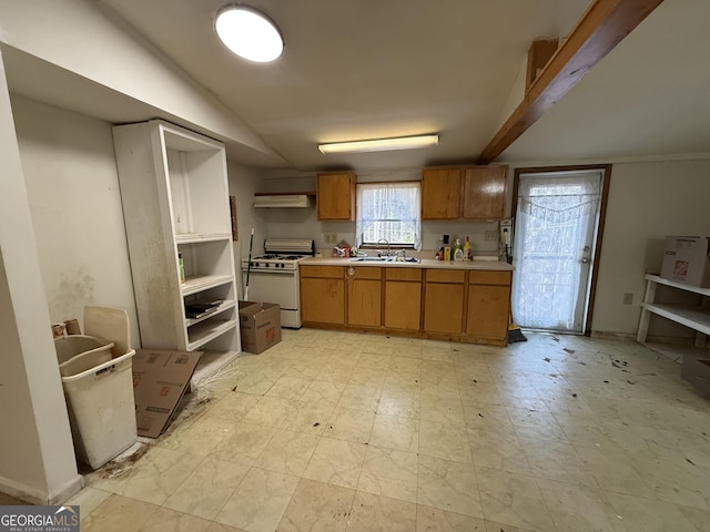 kitchen with white gas stove, a sink, light countertops, brown cabinets, and light floors