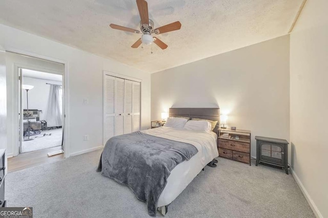 carpeted bedroom with ceiling fan, a textured ceiling, and a closet