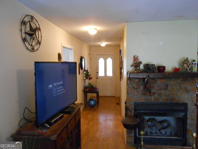 living room featuring wood-type flooring and a stone fireplace