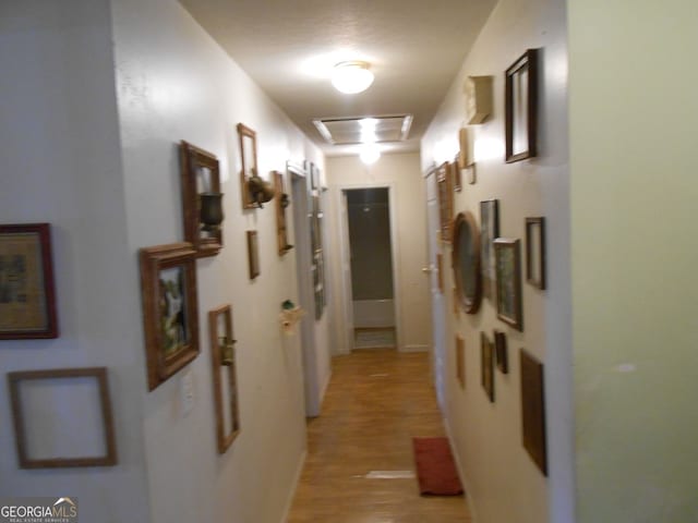 hall with light hardwood / wood-style floors and a textured ceiling