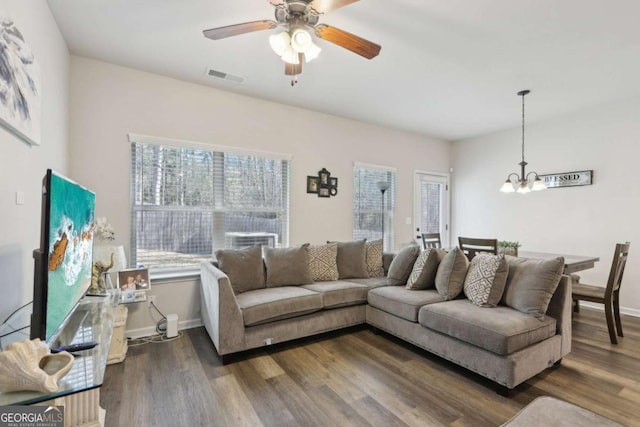 living room with ceiling fan with notable chandelier, plenty of natural light, and dark hardwood / wood-style floors