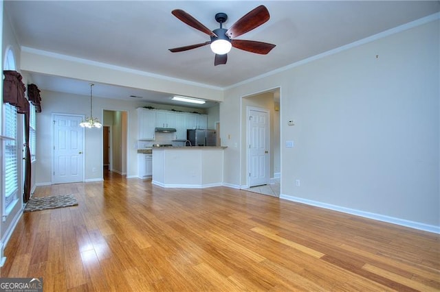 unfurnished living room with ornamental molding, ceiling fan with notable chandelier, and light wood-type flooring