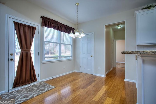 unfurnished dining area with a notable chandelier and light hardwood / wood-style floors