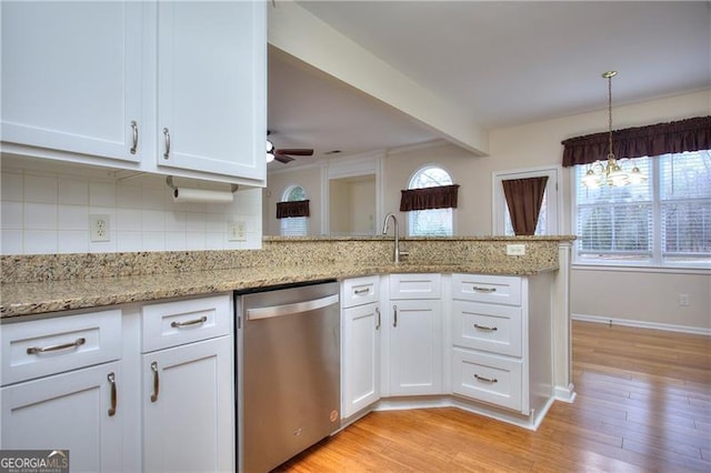 kitchen featuring light stone counters, stainless steel dishwasher, kitchen peninsula, and white cabinets