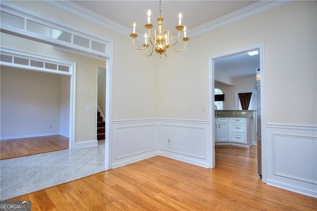 unfurnished dining area featuring crown molding, an inviting chandelier, and light hardwood / wood-style floors