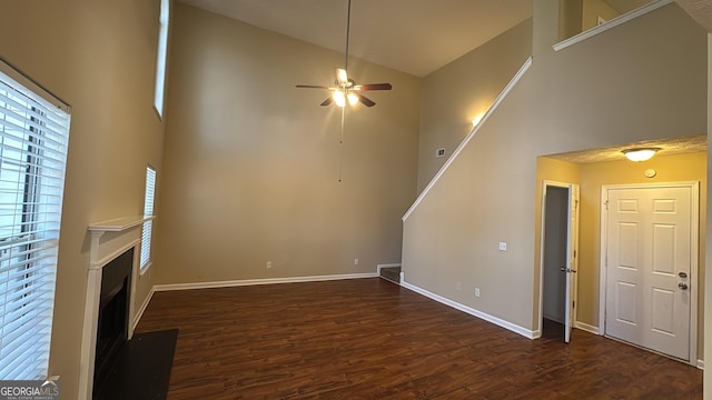 unfurnished living room with dark wood-type flooring, ceiling fan, and high vaulted ceiling