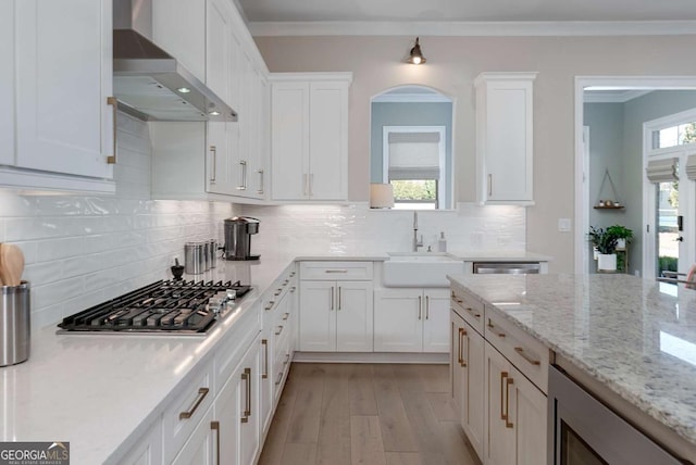 kitchen with appliances with stainless steel finishes, wall chimney exhaust hood, and white cabinetry