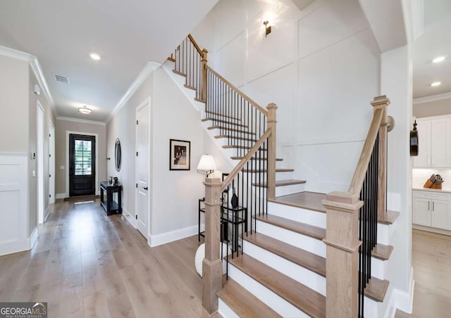 entrance foyer featuring crown molding and light hardwood / wood-style floors