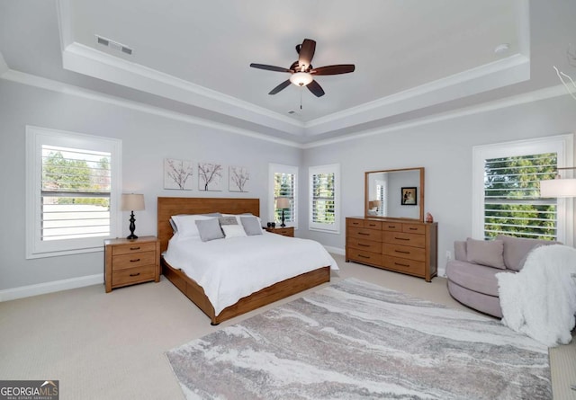 carpeted bedroom featuring ceiling fan, a tray ceiling, and multiple windows