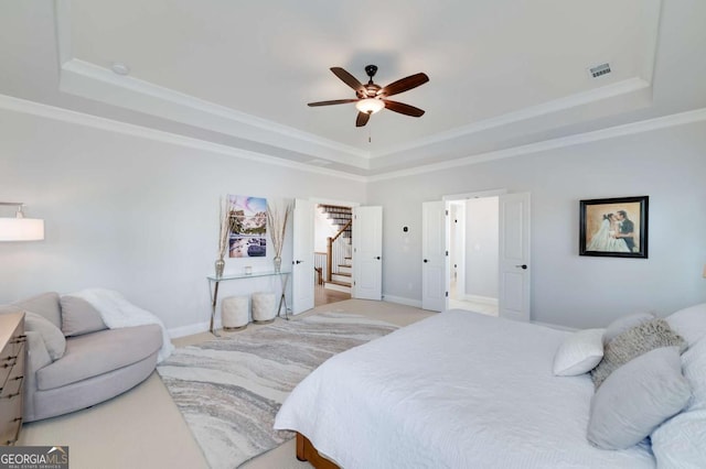 bedroom featuring a raised ceiling, light colored carpet, ceiling fan, and crown molding