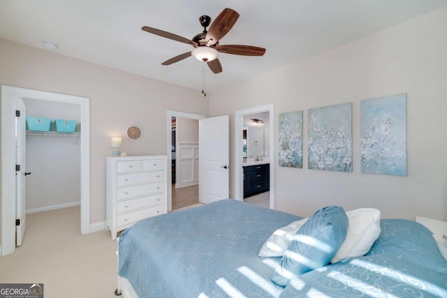 bedroom featuring a walk in closet, a closet, ceiling fan, light colored carpet, and ensuite bathroom