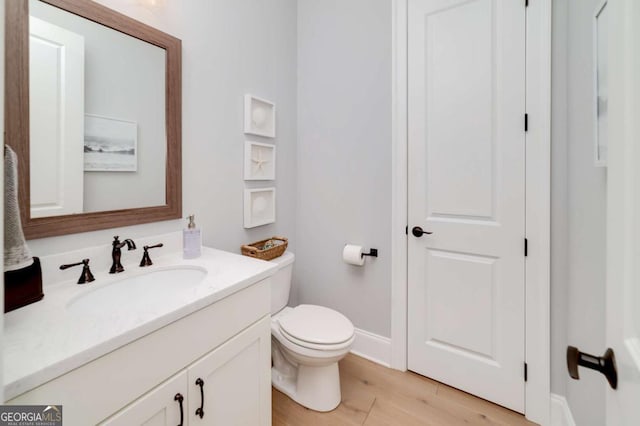 bathroom with hardwood / wood-style floors, toilet, and vanity