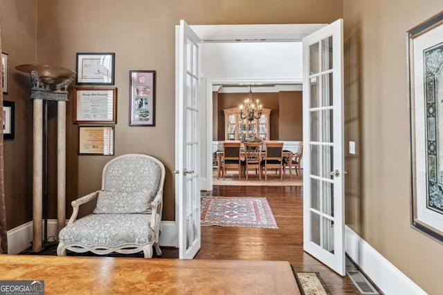 living area with wood-type flooring, french doors, and an inviting chandelier