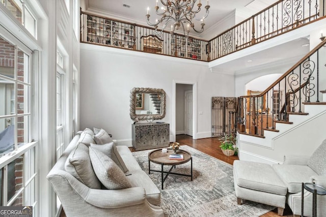 living room featuring ornamental molding, a high ceiling, a chandelier, and hardwood / wood-style flooring