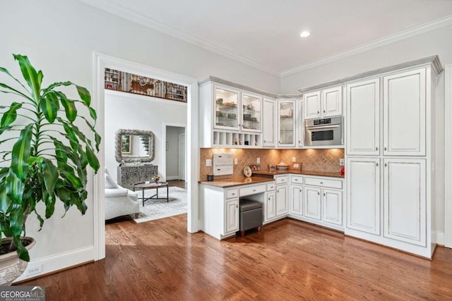 kitchen with white cabinets, dark hardwood / wood-style floors, ornamental molding, and oven