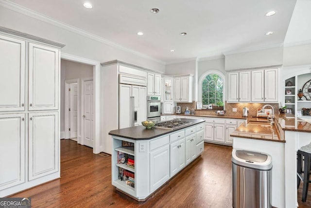 kitchen featuring white cabinetry, kitchen peninsula, appliances with stainless steel finishes, a kitchen breakfast bar, and sink