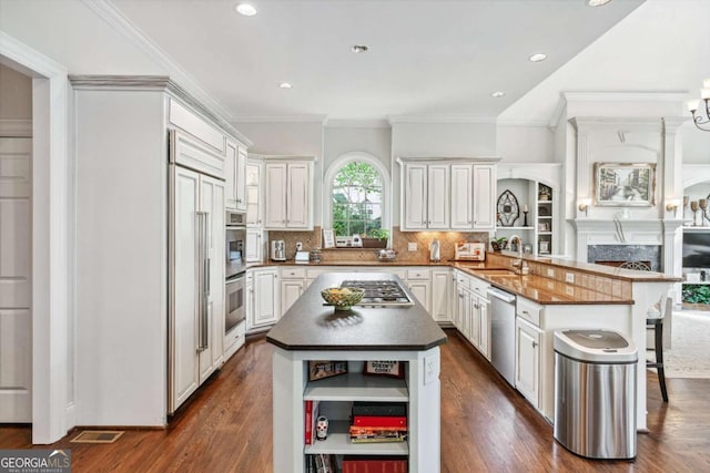 kitchen featuring appliances with stainless steel finishes, a center island, a kitchen bar, sink, and kitchen peninsula