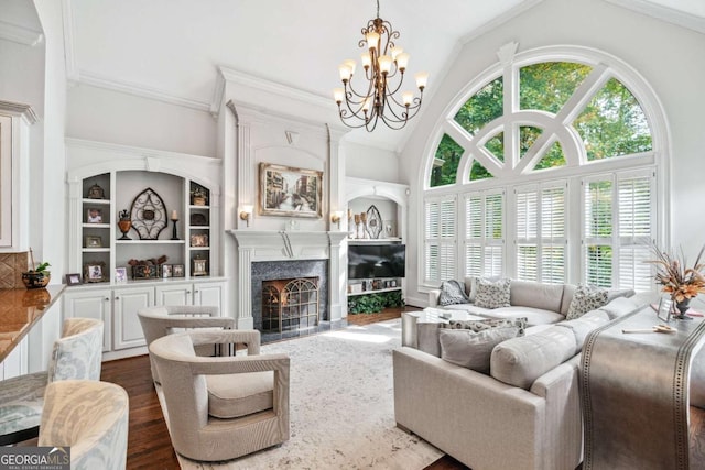 living room with dark hardwood / wood-style floors, crown molding, built in shelves, a high end fireplace, and a chandelier