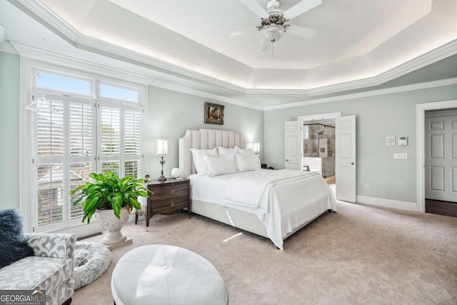 carpeted bedroom featuring ceiling fan, connected bathroom, a tray ceiling, and crown molding