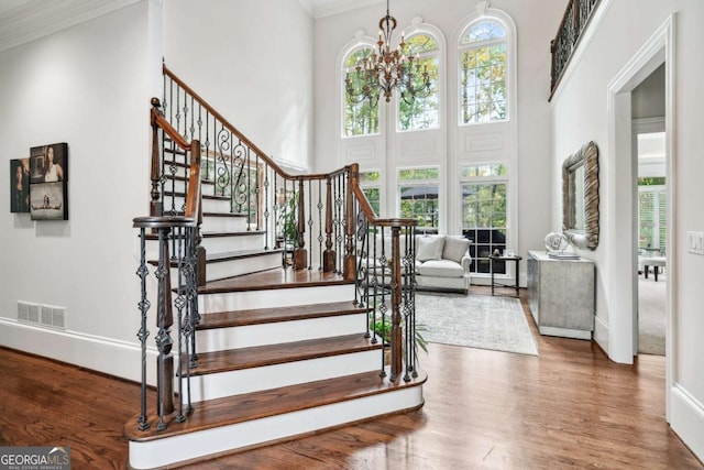 foyer featuring an inviting chandelier, crown molding, and a high ceiling