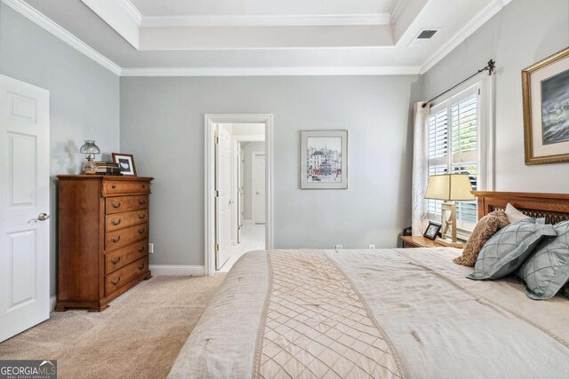 bedroom with ornamental molding, light colored carpet, and a tray ceiling