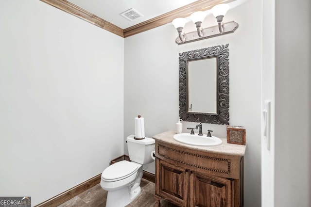 bathroom with toilet, ornamental molding, and vanity