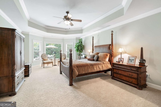 bedroom with ceiling fan, light carpet, a tray ceiling, and ornamental molding