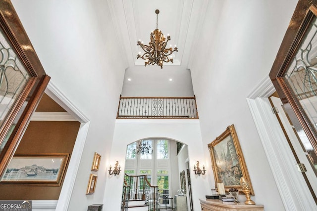 foyer with ornamental molding and a towering ceiling