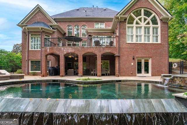 back of property featuring pool water feature, a patio area, french doors, and a balcony