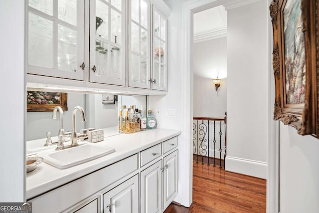 bar with sink, white cabinetry, dark hardwood / wood-style flooring, and ornamental molding