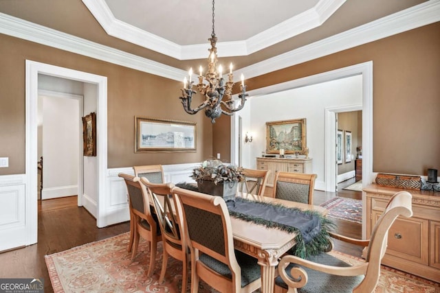 dining space with a raised ceiling, dark hardwood / wood-style floors, an inviting chandelier, and ornamental molding