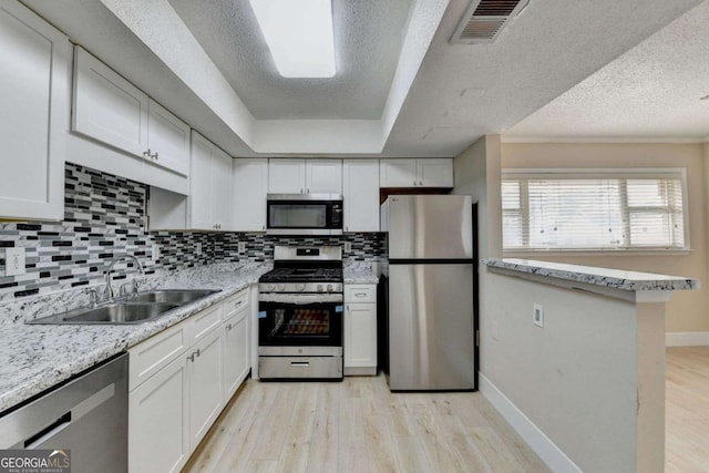 kitchen with white cabinets, backsplash, sink, and stainless steel appliances